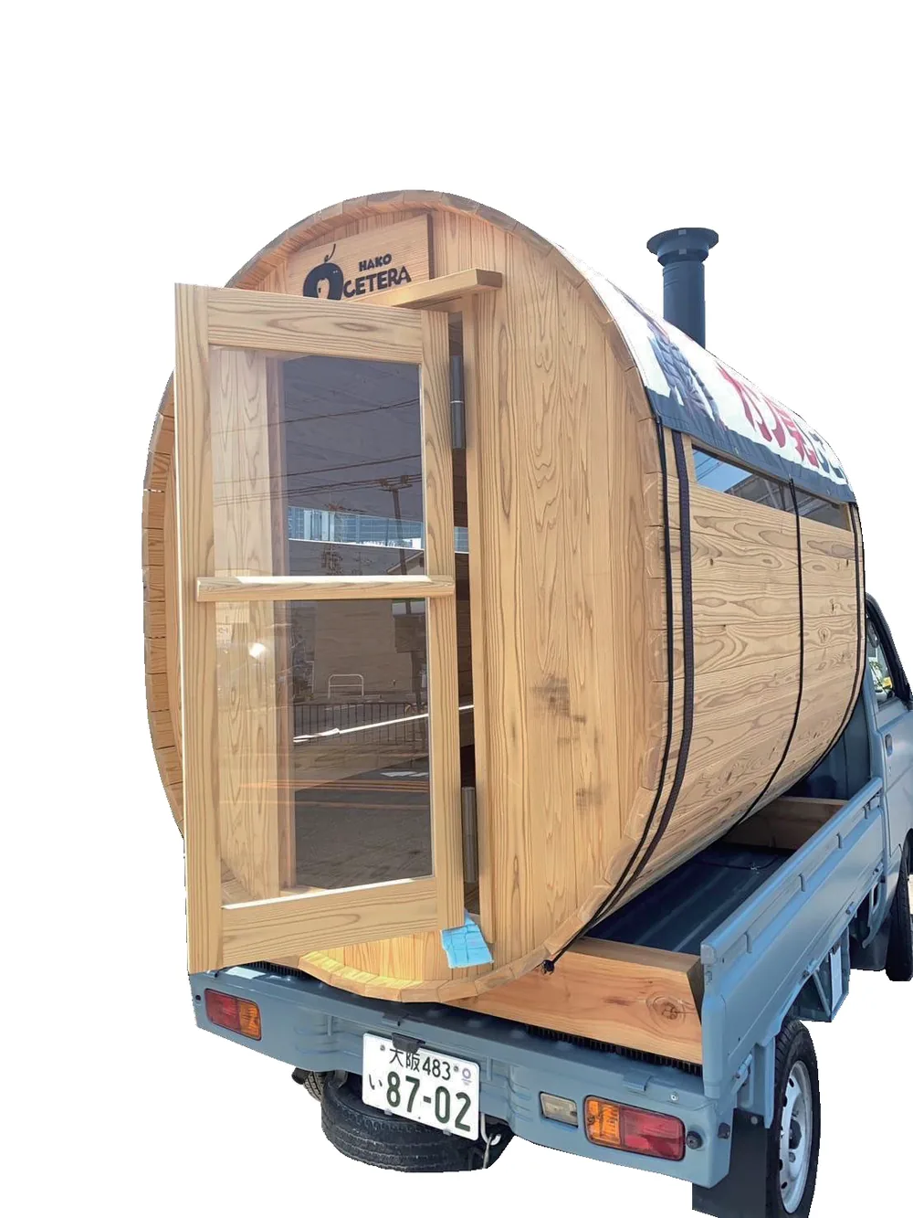 軽トラックの荷台に積まれた摂津サウナ。木の樽型で、天井にテントが張られている